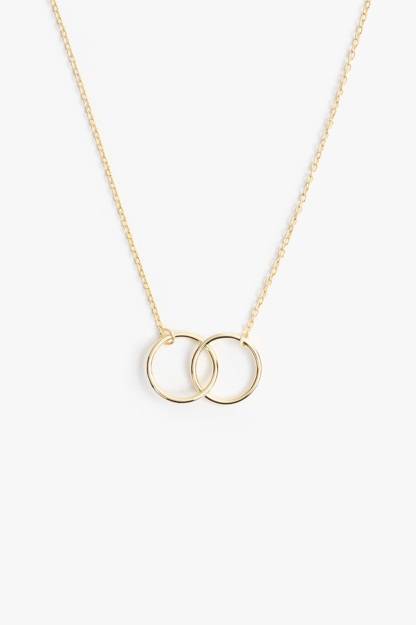 two gold circles on a gold necklace. this image is on a white background