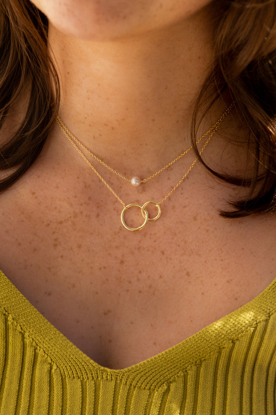 model wearing both resilient and nurture necklace. Image of neck with mustard coloured top